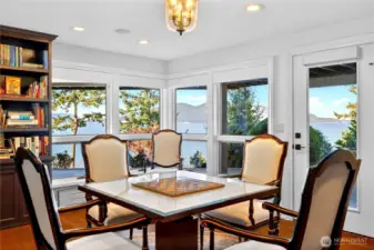 off of the media room is a richly finished library and game room with custom built-ins, water views, and access to the covered patio and hot tub.