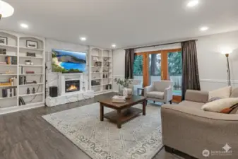 A delightful family room has a cozy fireplace banked by built-in shelves.