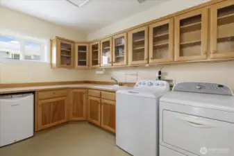 Huge laundry room includes the washer, dryer, & beverage refrigerator & lots of cabinetry for additional storage.
