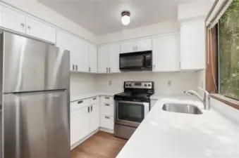 Kitchen features bright cabinetry, stainless steel appliances, and quartz countertops.