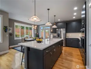Gleaming quartz countertops and tasteful lighting fixtures in this beautiful kitchen.