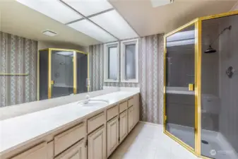 ¾ Bathroom with 2 separate single vanities (1 next to walk in closet) and counters, corner shower, & tile floor