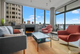 Cozy glass fireplace is flanked by bookshelves to display your treasures. Access to the deck is immediately behind the chairs.