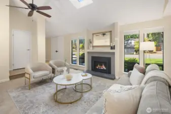 Living room with vaulted ceilings, gas fireplace, ceiling fans, and skylight.