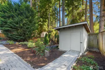 Landscaped backyard with paver walkway and storage shed.