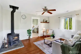 The living room features original wood floors and a cozy wood burning stove