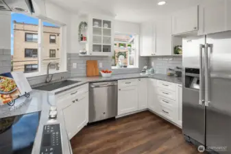 Tastefully an updated kitchen with a range hood, full height tile backsplash, slab quartz, newer custom cabinetry and appliances.  Light and bright with two windows!
