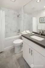 Guest bath has large soaking tub, beautiful 8 x 24 tile surround, new tile flooring, toilet and vanity/sink.