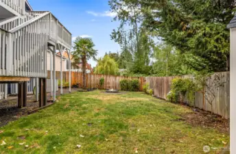 Fully fenced back yard with newer shed and fire pit.