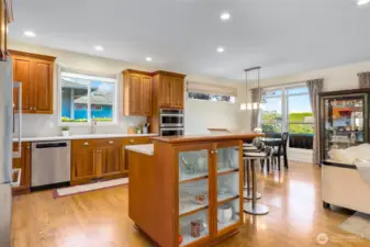 Huge kitchen with quartz countertops, butcher block island and a see through glass shelving