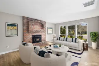 Virtually staged living room with brick fireplace, hardwood floors, and large windows in this Heritage Glen Puyallup home.