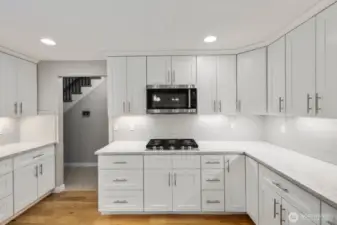 Chef-style kitchen featuring gas cooktop, extensive cabinet storage, subway tile backsplash, and sleek stainless steel appliances.