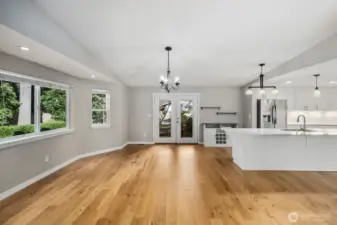 Open-concept main living area featuring hardwood floors, dining space, and a bright kitchen with quartz island and stainless appliances.
