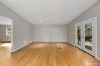 Large family room with recessed lighting, hardwood floors, and glass doors providing access to the backyard patio.