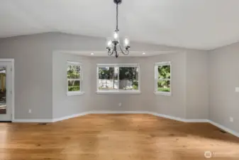 Dining area framed by multiple windows that bring in natural light and views of the surrounding yard.