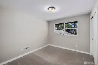 Comfortable bedroom with plush carpet, large window for natural light, and closet storage.