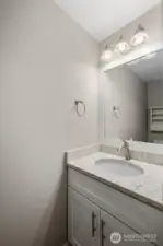 Main-level powder bathroom with modern vanity, updated lighting fixture, and large mirror.