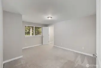 Spacious bedroom with soft carpeting, neutral walls, and large window bringing in natural light.