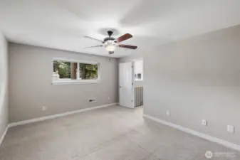 Light-filled bedroom with wide window, soft carpeting, and flexible space for furniture or home office setup.