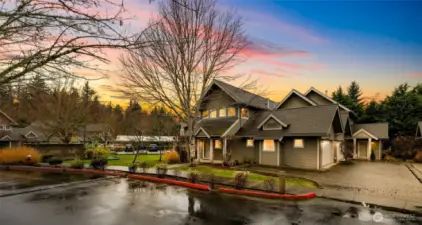 Peaceful corner setting at dusk with mature landscaping and a welcoming covered entry. Beautiful curb appeal in a quiet, well kept community.