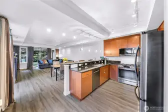 Spacious open concept living, dining, and kitchen area with large windows and views of the landscaped grounds.