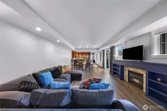 Expansive great room with a gas fireplace, built-ins, large windows, and a seamless flow into the dining and kitchen areas.