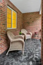 A lovely covered front porch framed in brick, a welcoming space to sit and chat.