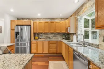 The kitchen is stylishly finished with full-height stone walls, slab countertops, and sleek stainless appliances.