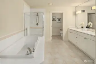 Primary ensuite five piece bath with tile floors and water closet.