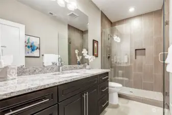 Guests don't need to leave the action-zone. Spacious 3/4 bathroom with large sink cabinet and granite countertops, full length mirror, glass shower enclosure, floor-to-ceiling tile surround, inset shampoo niche and tiled floors.