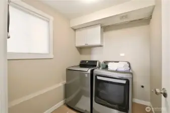 A look at the laundry room with a rod for hanging laundry and cabinet for detergents.