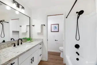 The en-suite primary bath was fully remodeled and features lovely Quartz counters, tiled shower surround, new fixtures, and hardware, along with a linen closet opposite the toilet.