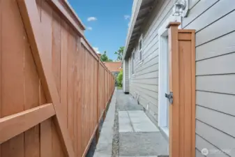 The north side of the house and gate leading to back yard. There is a stone paver patio right outside the man door of the garage for your garbage cans.