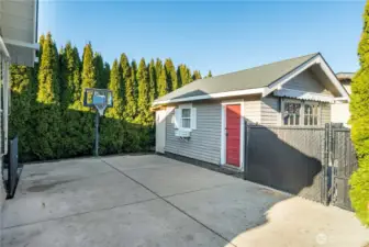 Well-screened back yard patio. View toward entry door to garage and basket ball hoop.