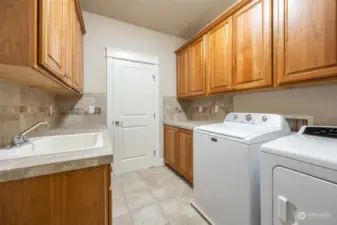 Convenient laundry room includes mud sink, tons of storage and plenty of counter space for folding.
