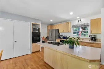 Large kitchen island with cooktop.  Notice the window above the kitchen sink and access to the garage left of the fridge.