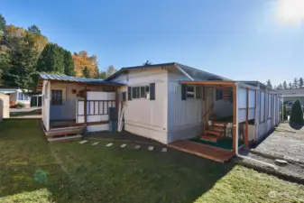 Back of home / covered work bench on left and covered porch with golf putting green on the right.