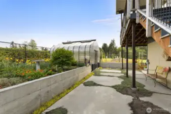 Serene garden walkway with vibrant plantings and access to the greenhouse.