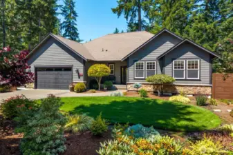 Front view of home -- beautifully landscaped, sprinkler sytem, fiber cement siding, stone accents, and 2-car garage with space for a golf cart.