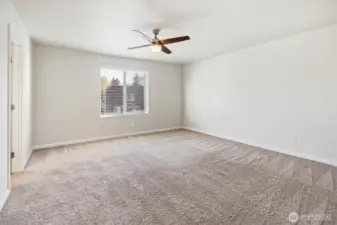 Sunlit primary bedroom complete with ceiling fan for comfort
