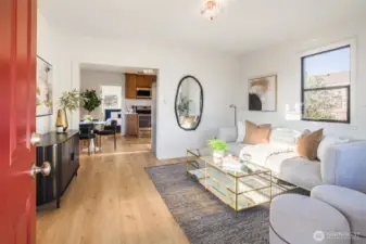 Bright, open living area featuring new LVP flooring, fresh paint, and seamless flow into the dining and kitchen spaces.