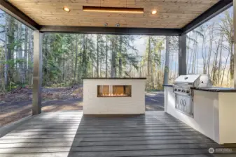 Covered outdoor living with a gas fireplace and a bulit-in Kitchen-Aid grill.