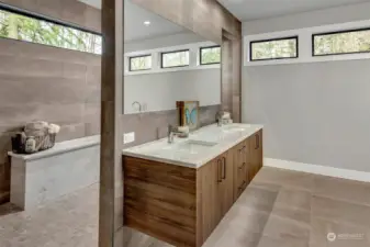 Luxury primary bathroom with floating vanity, marble counters/shower bench, and heated flooring.
