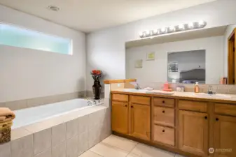 En-suite bathroom with new tile flooring, relaxing soaking tub, dual sinks, and plenty of counter space.