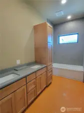 Main floor bath with heated tile flooring, under counter dual sink vanity, custom Alder cabinetry, tub to ceiling custom tile shower.