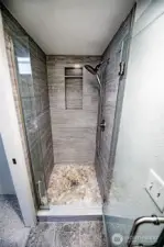 Newer porcelain tile on both floor and walls with glass door in primary bathroom.