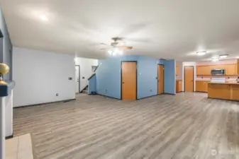 A large greatroom makes a terrific living space. The front door is in the center of this photo, with the downstairs bathroom just to the left of the door, and the stairs to upstairs on the right. The door in the middle photo is a large under stair closet. The door to the right exits to the garage. The door in the kitchen is a large pantry.