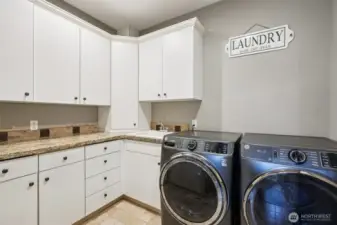 Stylish and highly functional, this laundry room features durable tile floors, granite countertops, and abundant cabinetry for effortless organization. A built-in ironing board station adds convenience, while sleek modern appliances (not included in sale) showcase the space’s capacity for both beauty and utility. Smart layout and ample storage make laundry day a breeze
