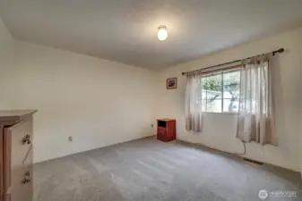 The second guest bedroom with wall to wall carpet and bright window.