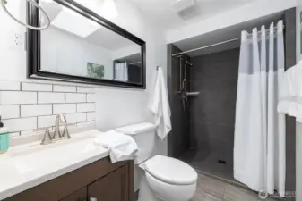 The bathroom has a walk in tiled shower.